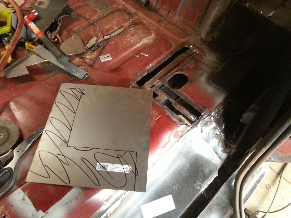 Sheet metal with markings on a rusted vehicle floor, with tools in the background.
