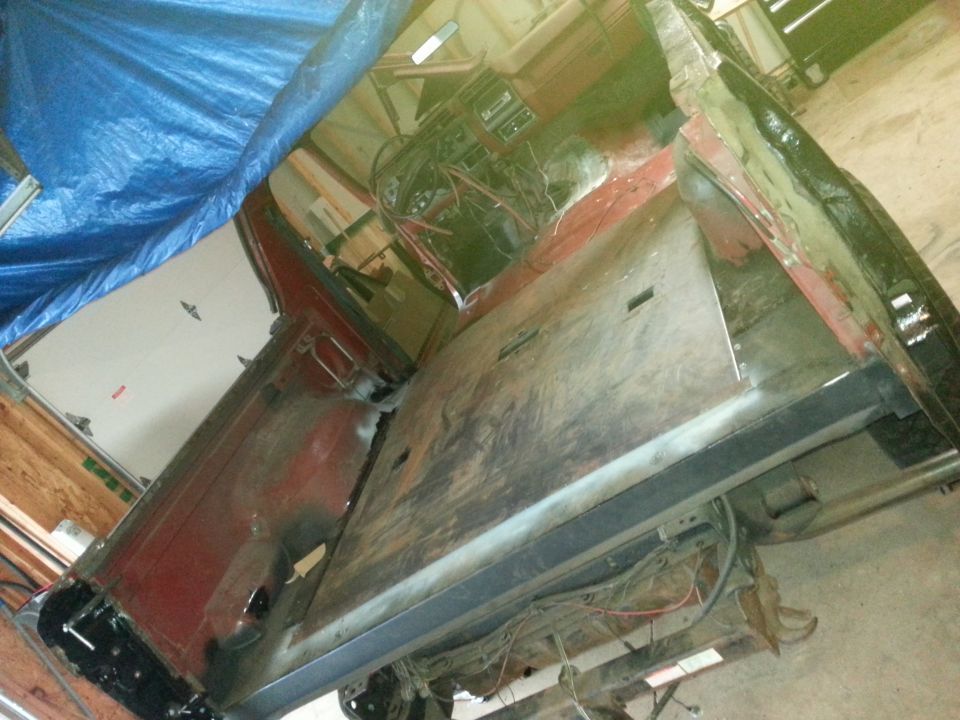 Overhead view of a classic Ford Bronco interior with exposed wiring and a blue tarp.