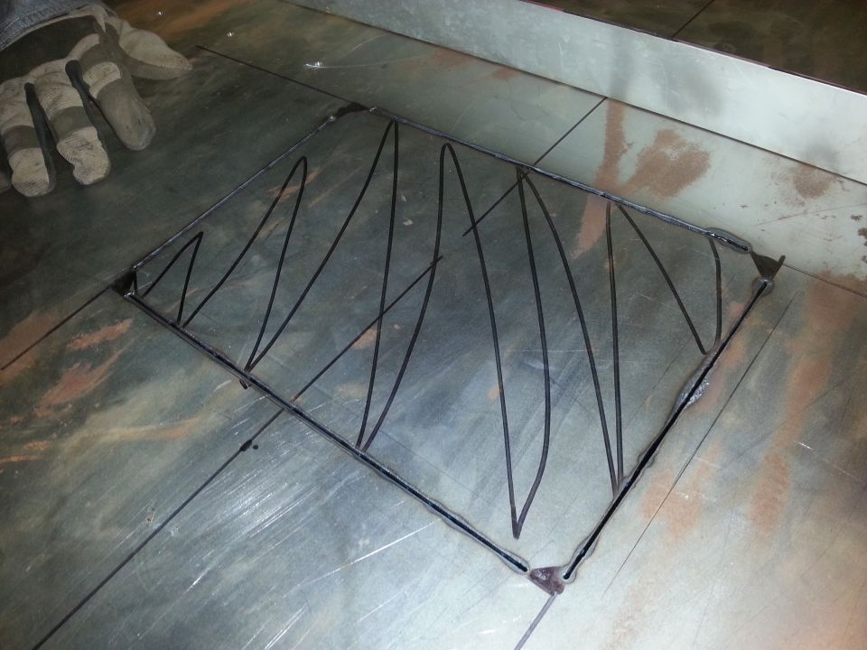 Gloved hand on metal surface with a metal frame and wire bracing.