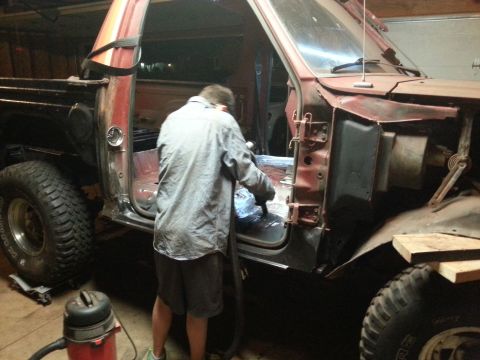 Person vacuuming interior of a red and black pickup truck.