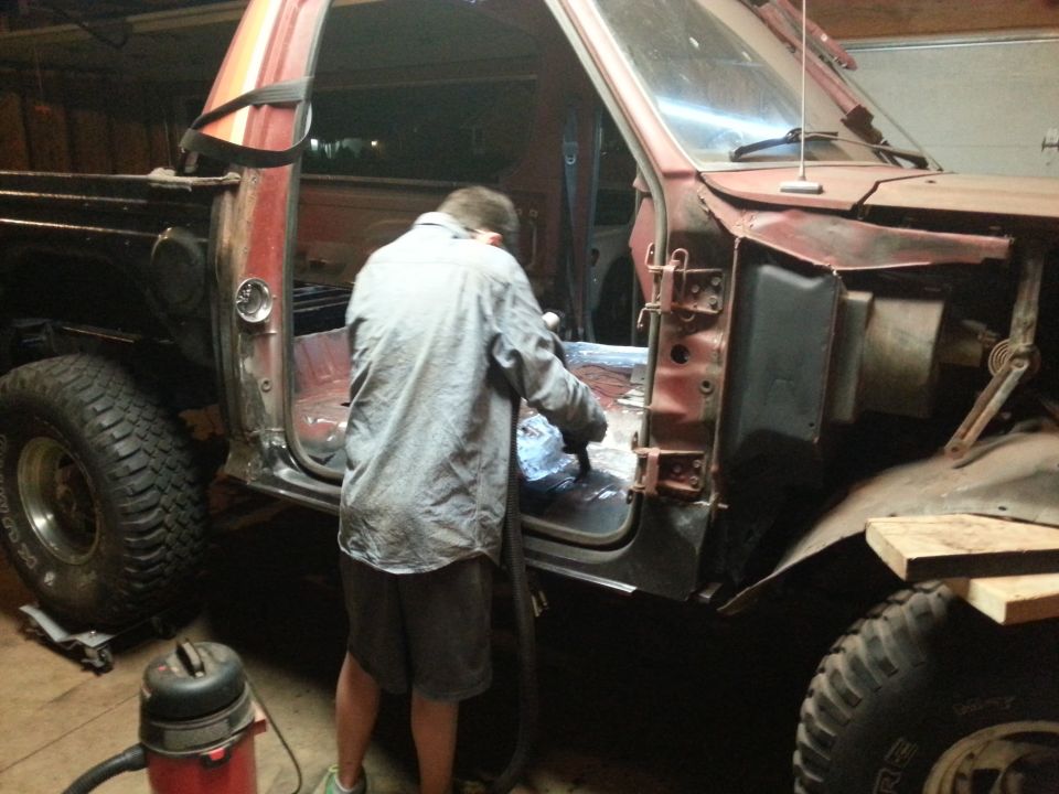 Person vacuuming interior of a red and black pickup truck.