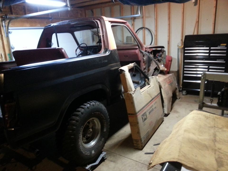 Dark SUV in garage with doors removed, red interior parts visible.