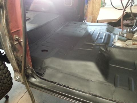 Interior floor of a vehicle, prepped for work, showing floor pan and door frame.