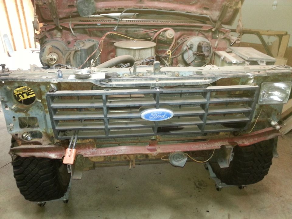 Front view of a rusty 1980s Ford truck or SUV grille with Ford emblem.