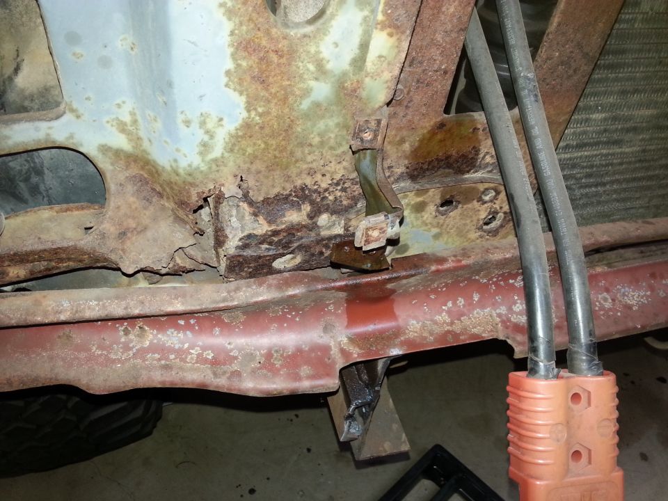 Heavily rusted vehicle undercarriage with hoses and electrical connector.