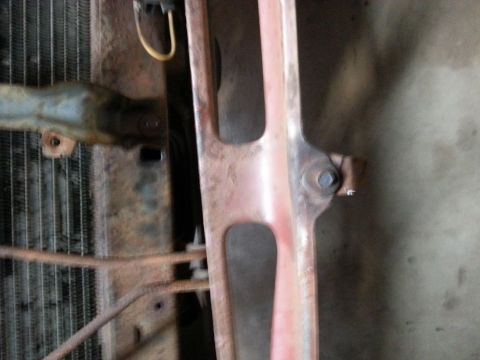 Close-up of a vehicle radiator and grille support, showing rust.