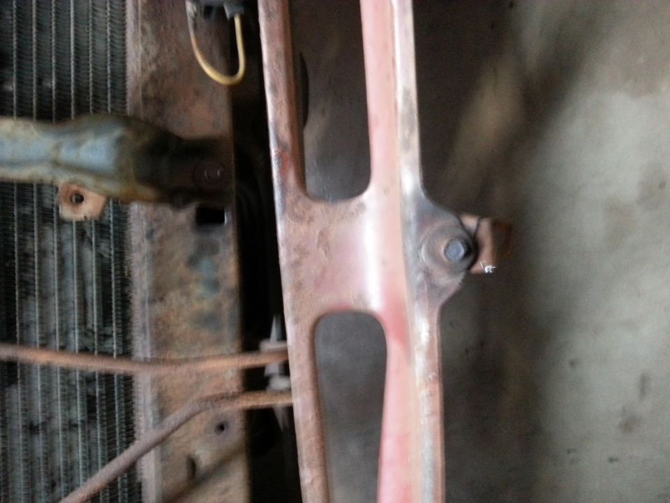 Close-up of a vehicle radiator and grille support, showing rust.