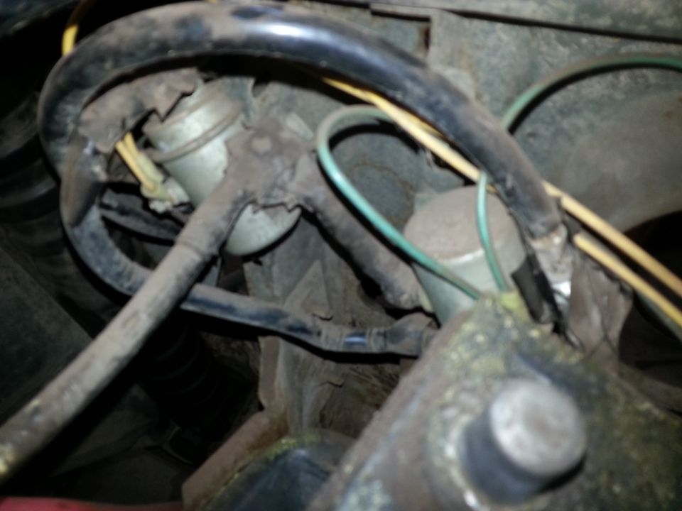 Engine bay with visible wiring, hoses, and cylindrical components.