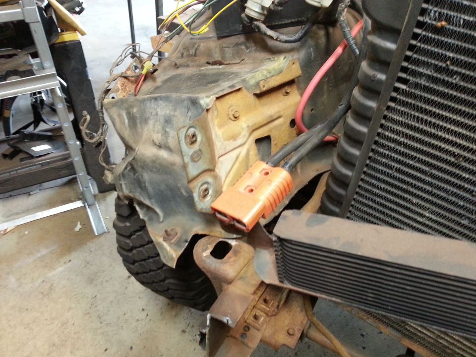 Vehicle front end with radiator, wiring, and orange connector.
