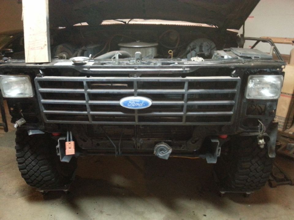 Front of a black Ford Bronco with hood open, showing grille and engine