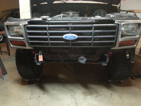 1984 Ford Bronco front view, hood open, showing grille, headlights, and tires.
