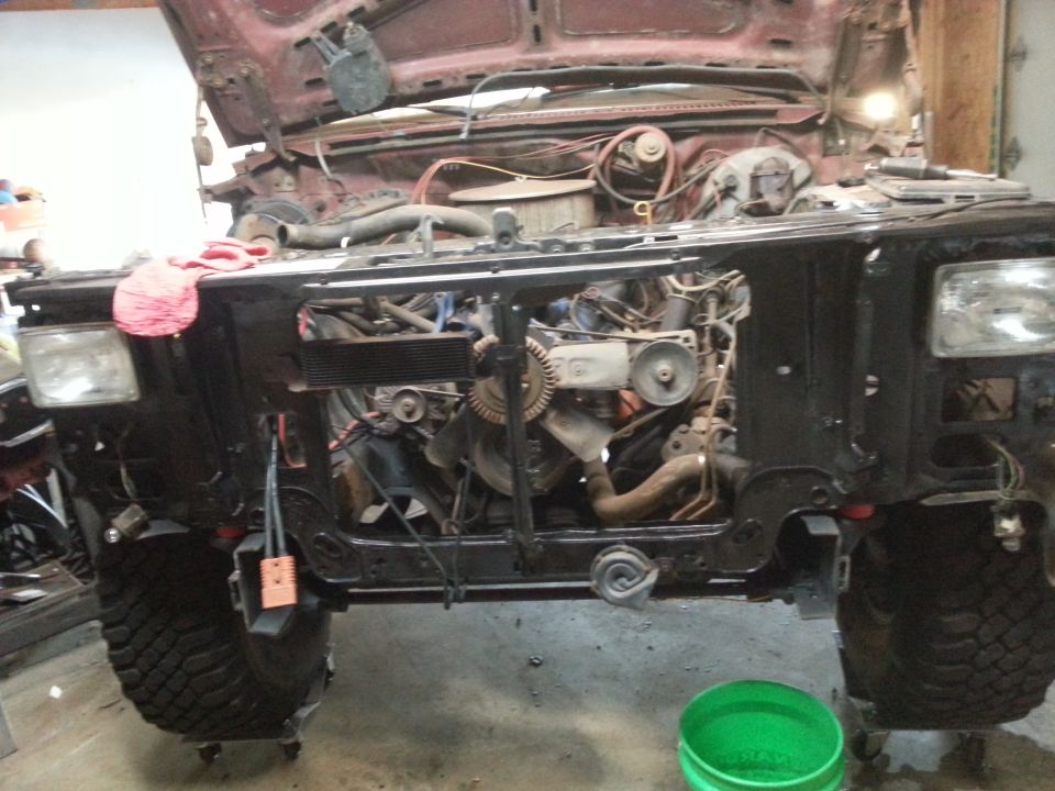 1984 Ford Bronco front end with hood open, engine exposed, on jack stands.