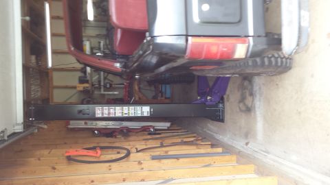 Underside of a vehicle on a car lift in a garage.