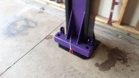 Base of a purple and black automotive lift post with an orange pull pin.