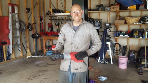 Man holding a rotary hammer drill in a garage