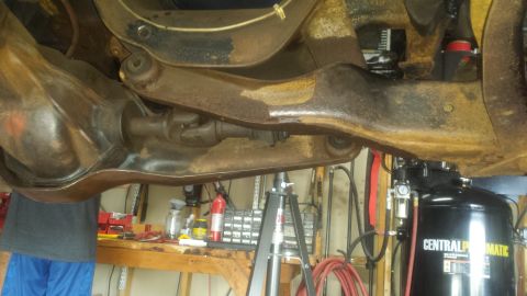 Underside of vehicle rear axle, differential, driveshaft, suspension, and air compressor.