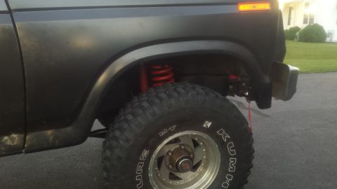 1984 Ford Bronco front fender and tire with red coil spring.