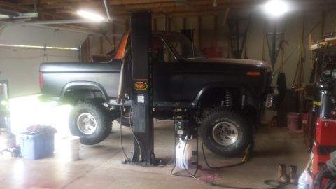 Black Ford Bronco on a car lift in a garage.