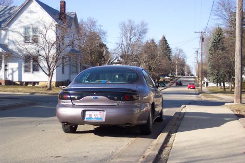 1996 Ford Taurus - A 1996 Ford Taurus is parked on a residential street under a clear sky.