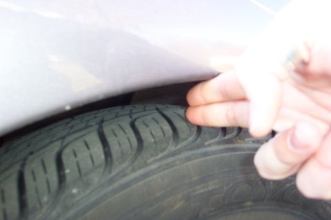 1996 Ford Taurus - A hand checks the clearance between the tire and fender, indicating a potential issue or modification.