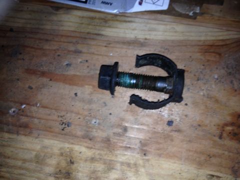 Bolt with a broken black bracket on a wooden surface