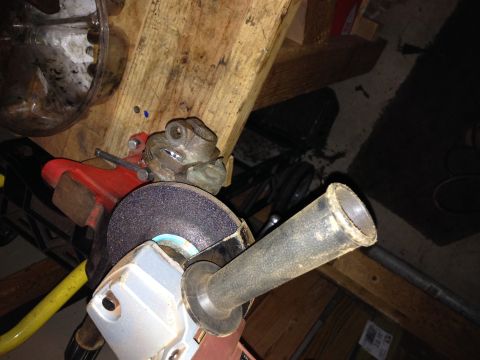 Grinding wheel and handle of a power tool, with a metal frog figurine clamped in a vise