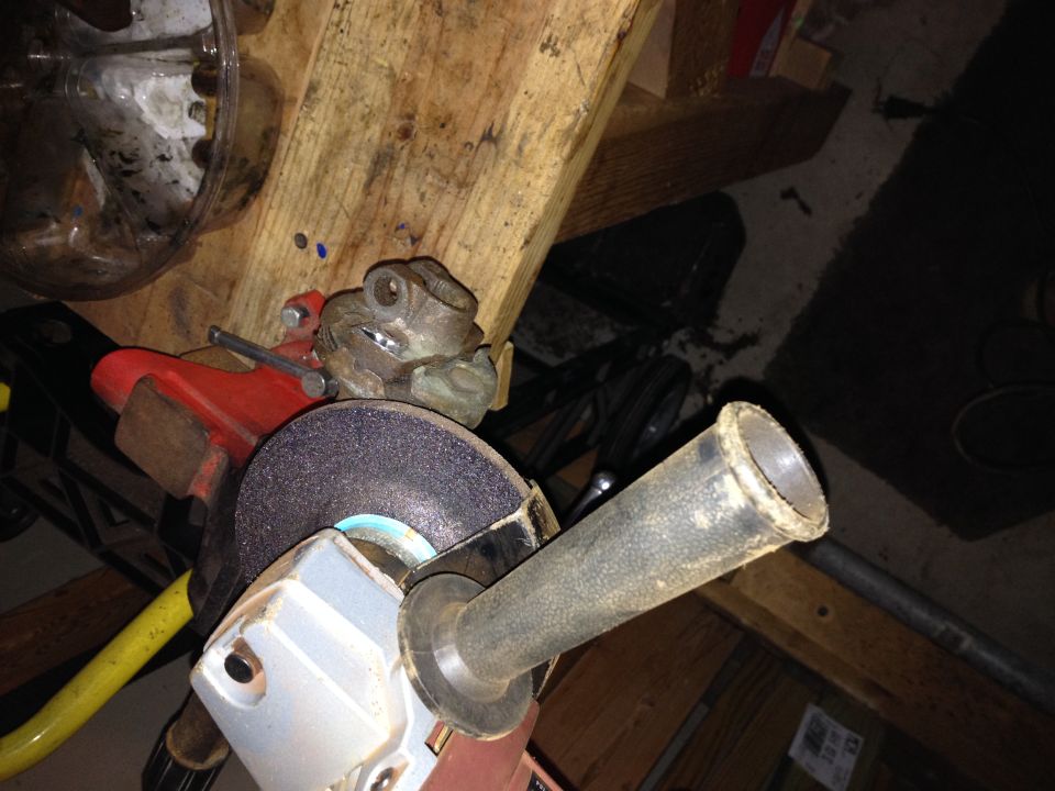 Grinding wheel and handle of a power tool, with a metal frog figurine clamped in a vise