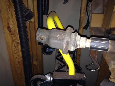 Rusty metal automotive part with yellow support, on a stand with wheels