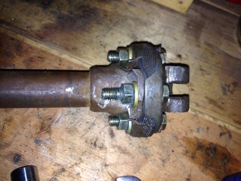 Close-up of a driveshaft U-joint with bolts and a rubber boot