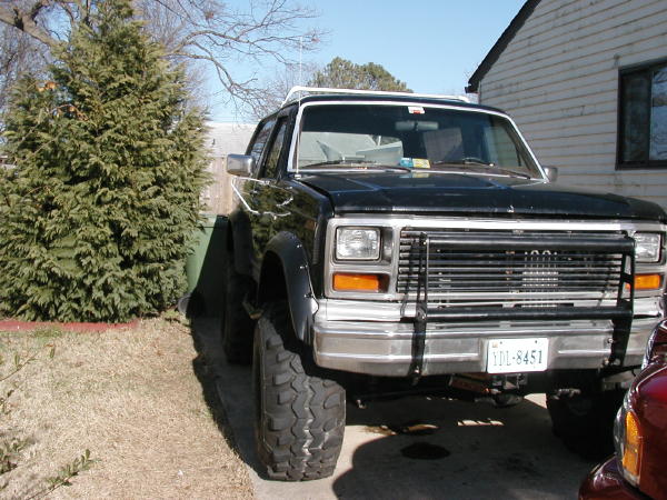 Black Ford Bronco with brush guard and lifted suspension, parked in a driveway