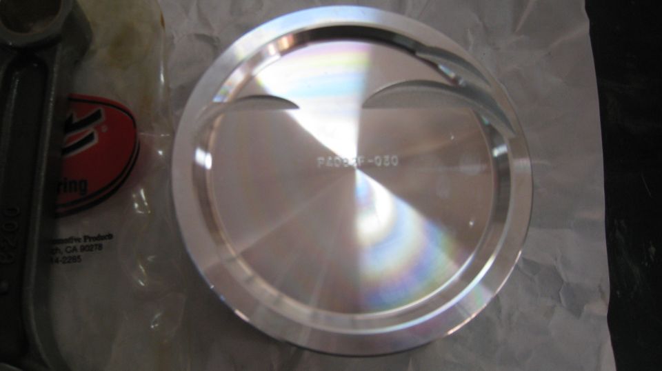 Polished aluminum piston with part number P4098F-030, connecting rod, and logo.