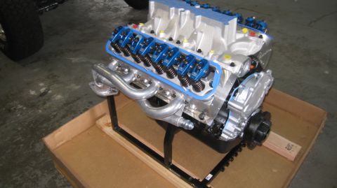 1996 Ford Bronco - A custom V8 engine with blue valve covers and chrome exhaust headers is mounted on a black stand, resting inside a cardboard box. The engin…