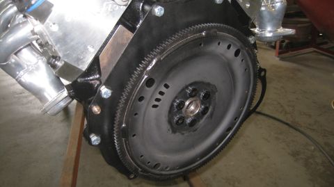 1996 Ford Bronco - A close-up view shows the flywheel and starter ring gear attached to the engine block of a vehicle. The shiny exhaust headers are visible o…