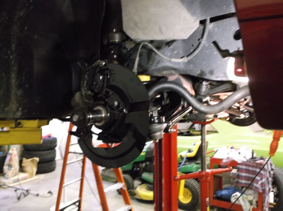 Underside of a vehicle showing front suspension, brake assembly, and sway bar.