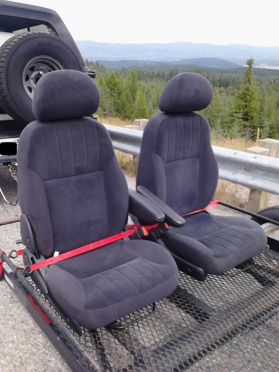 Two dark blue car seats on a trailer with a scenic mountain view.