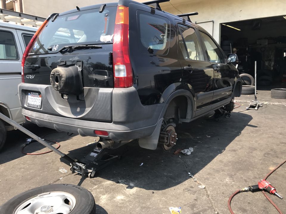 Black Honda CR-V with rear wheels removed, jacked up in a repair shop.