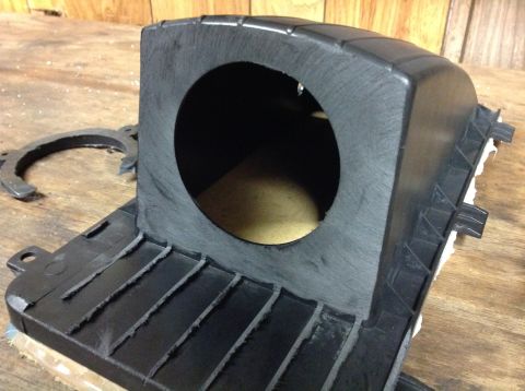 1996 Ford Bronco - A custom-cut black plastic housing with a circular opening sits on a wooden surface. A metal ring with cutouts is visible to the left of th…
