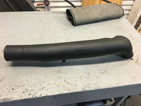1996 Ford Bronco - A black K&N intake tube is shown lying on a workbench. The tube has a curved end and the K&N logo is visible on its side.