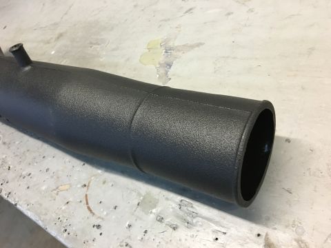 1996 Ford Bronco - A close-up, angled view of a textured black intake tube, possibly for a 1996 Ford Bronco, resting on a concrete surface.