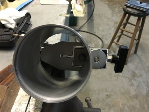 1996 Ford Bronco - A close-up view of a throttle body with a lever mechanism inside, mounted on a workbench. The throttle body is silver and appears to be par…