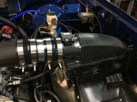 1996 Ford Bronco - A close-up view of the engine bay of a 1996 Ford Bronco, focusing on the intake system. The image shows a black intake tube secured with mu…