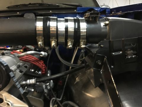 1996 Ford Bronco - A close-up view of the engine bay of a vehicle, showing a black intake tube secured with multiple metal clamps. Visible engine components i…