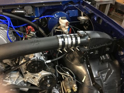 1996 Ford Bronco - A close-up view of a modified engine bay, featuring a black K&N intake system with chrome clamps, a supercharger, and bright blue spark plu…