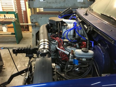 1996 Ford Bronco - The engine bay of a blue vehicle, likely a 1996 Ford Bronco, is shown with various engine components, including a K&N air intake and blue s…