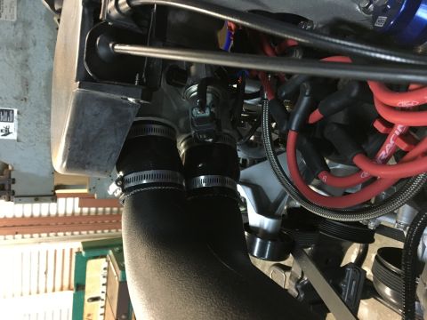 1996 Ford Bronco - A close-up view of a vehicle's engine bay, focusing on the intake system and spark plug wires. The intake tube is black and secured with ho…