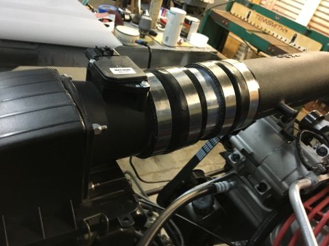 1996 Ford Bronco - A close-up view of an engine bay shows a black intake tube with multiple silver hose clamps connecting to a black air intake box. A black M…