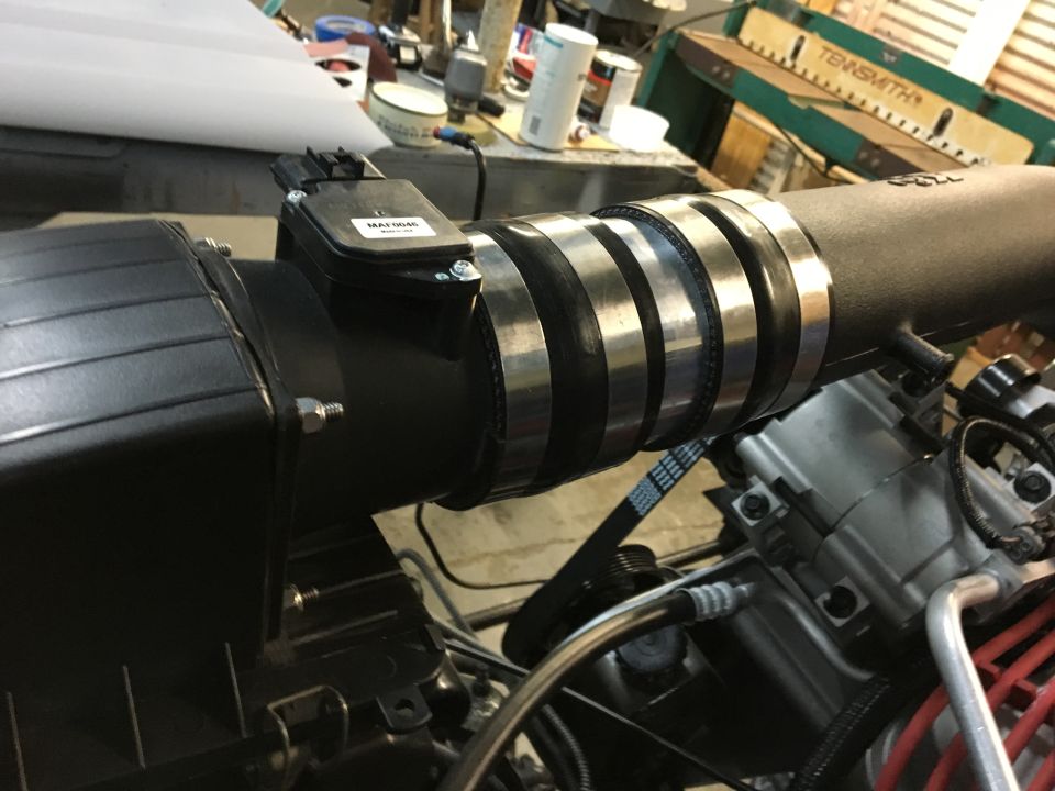 Close-up of engine bay with black intake tube, MAF sensor, and hose clamps.