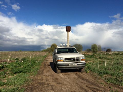 1993 Ford Bronco - A white 1993 Ford Bronco is parked on a dirt road in a grassy field with a water tower in the background.