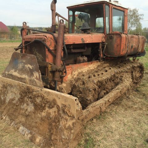 1993 Ford Bronco - A heavily mud-caked, orange tractor with a front-end loader sits in a grassy field.