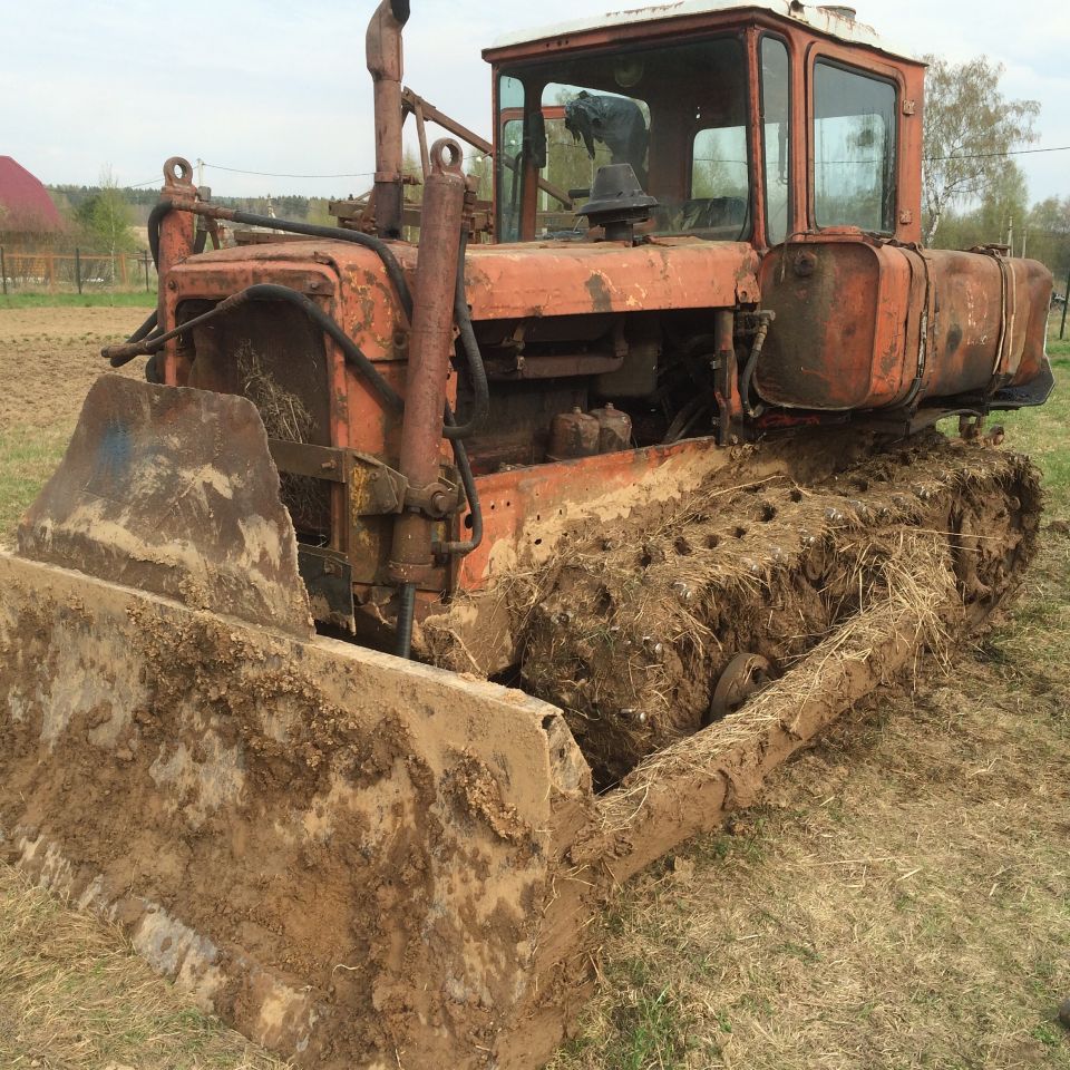 Muddy orange tractor with front loader in a field.